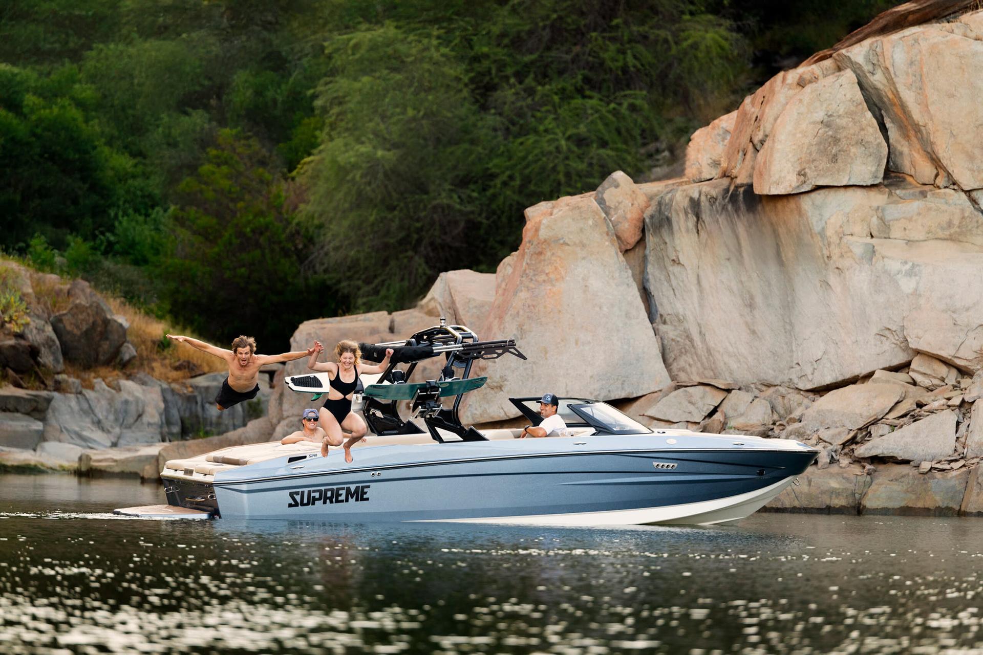 A Supreme S240 on the water with riders jumping from the bow